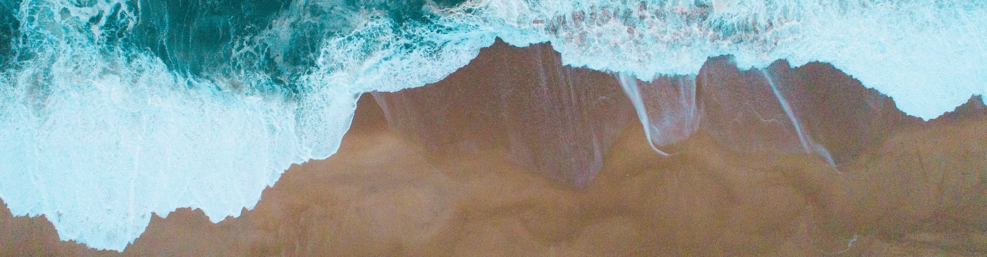 aerial shot of sea waves hitting sandy shore