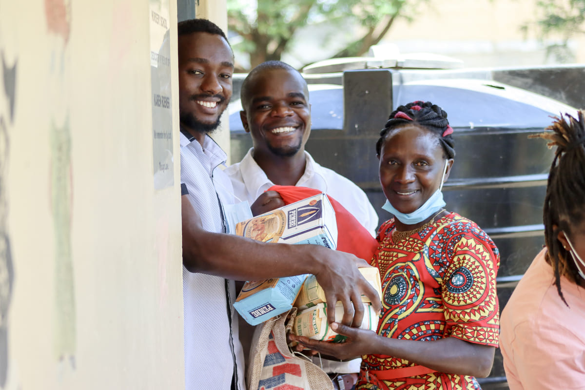 3 people smiling while providing food donations